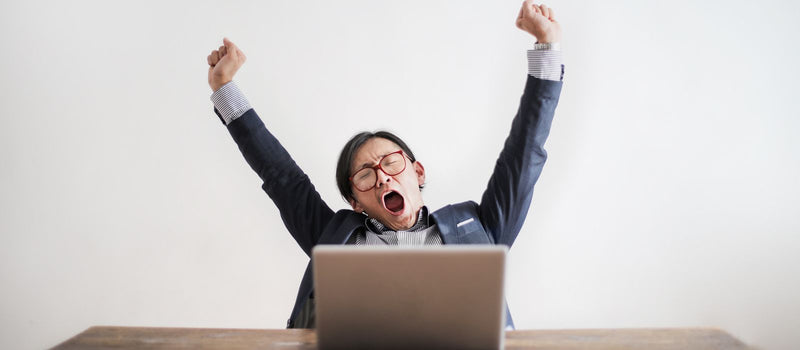 Tired man yawning at his laptop after a sleepless night