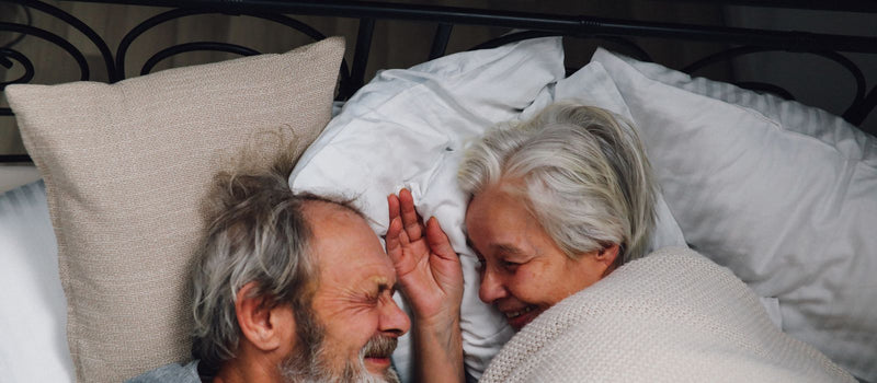 Older couple smiling at each other in bed