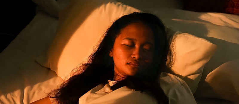 Woman resting peacefully in bed in a calm, softly lit bedroom