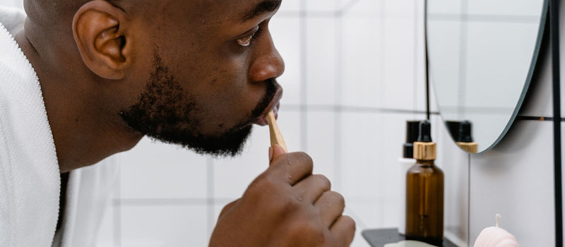 Man brushing his teeth while looking in a bathroom mirror