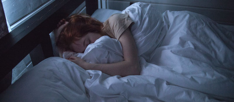 Woman asleep in bed at night with a book